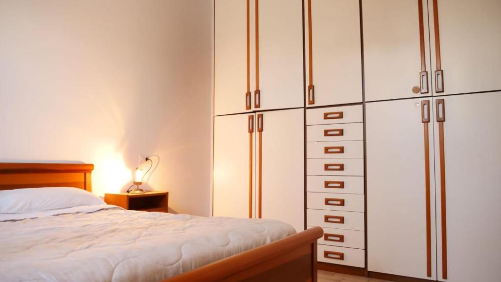 A bedroom with a wooden bed, white bedding, bedside table, and built-in wardrobes.