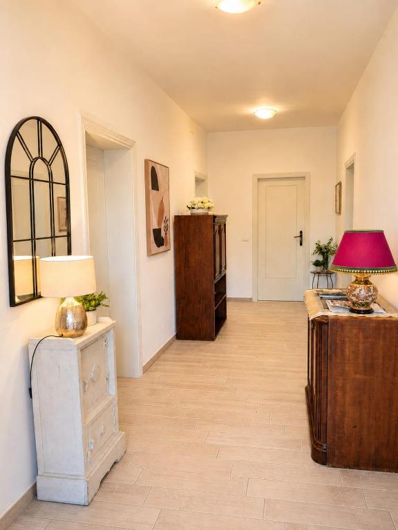 A bright interior hallway with multiple doorways, wooden furniture, lamps, and framed wall decor.